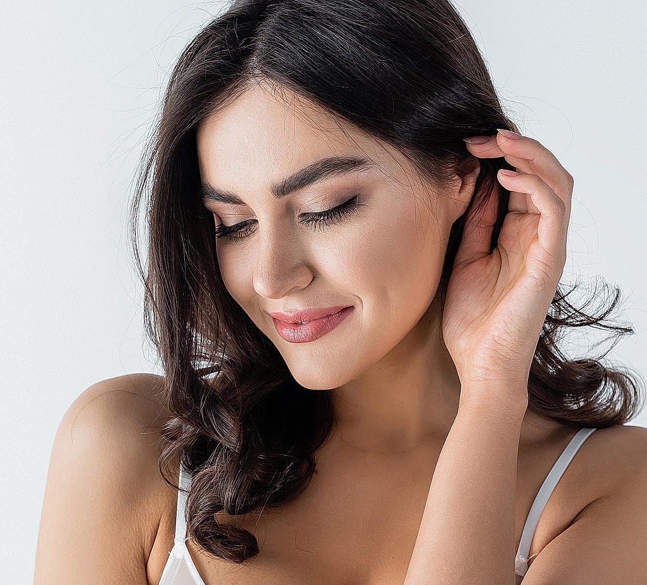 Smiling woman with wavy hair on light background.