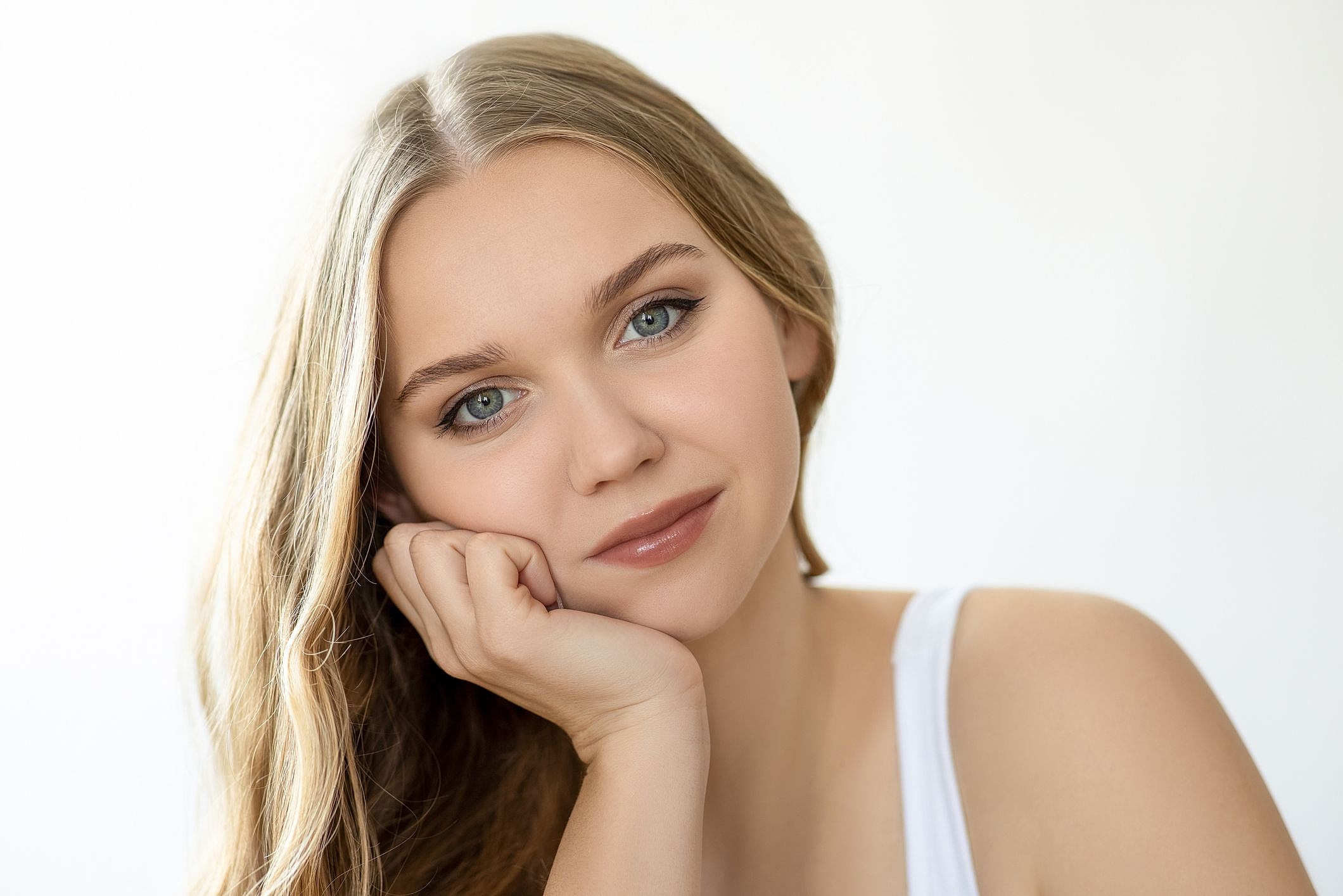 Young woman with long hair resting her chin.