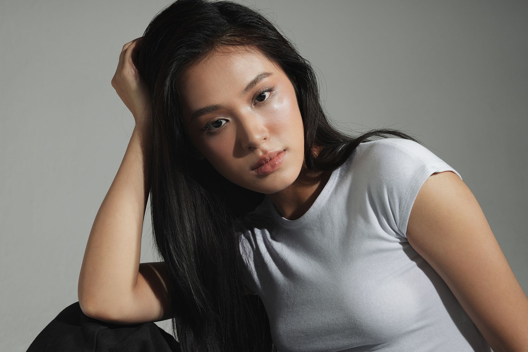 Young woman posing with long hair and white shirt.